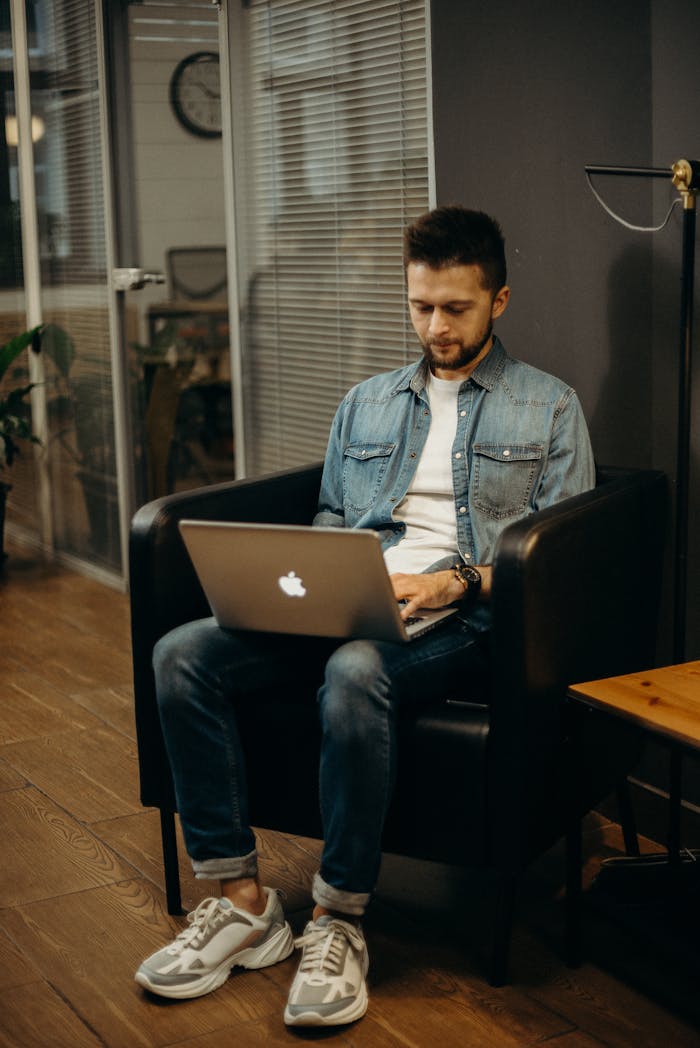 Adult man working on a laptop in a modern office setting, showcasing digital nomad lifestyle.